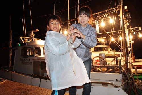 釣れたイカを手にする親子