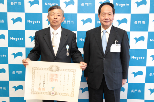 勲章を胸に受章を喜ぶ小林さん（左）