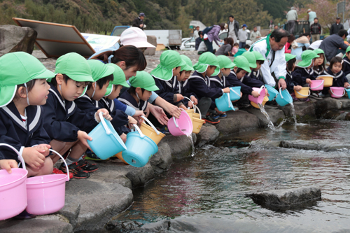 一斉にアユを放流する園児ら