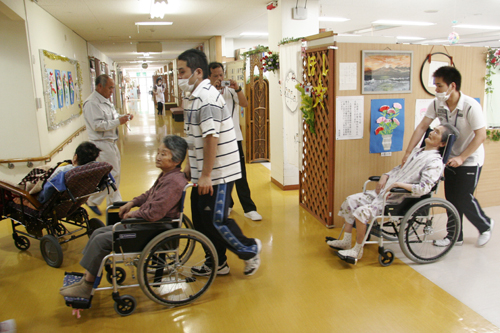 車いすの人を避難させるスタッフ