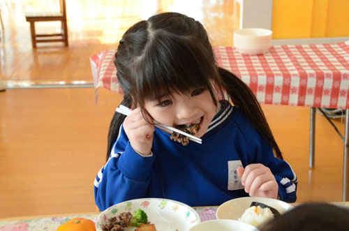 鯨の竜田揚げを食べる園児