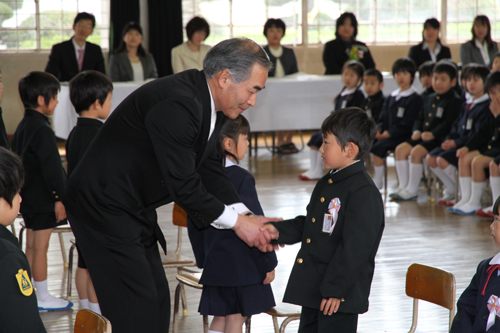 大きな返事をした新入生と握手をする山本校長