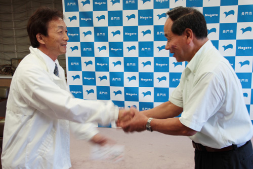 激励費を手渡し固い握手を交わす