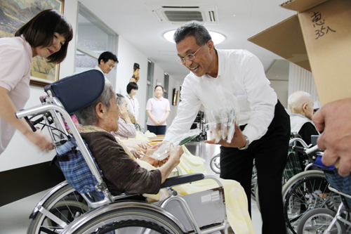 お菓子を手渡す末永組合長（右）