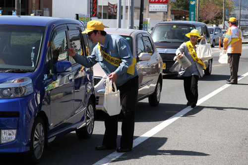 停車中の車に啓発グッズを手渡す
