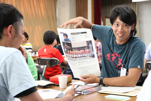 ポスターを手に通地区の現状を話す馬來隊員（手前は三隅地区担当の津田隊員）