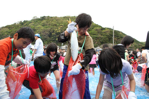 大きな魚を手に取る子どもたち