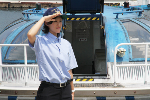 船の前で敬礼する岡村さん