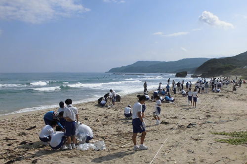 広い大浜海岸で漂着物を拾う生徒ら