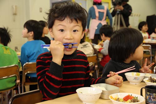 おいしそうにくじらの竜田揚げをほおばる