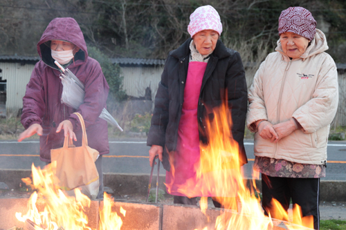 どんど焼きの火にあたり無病息災を祈る