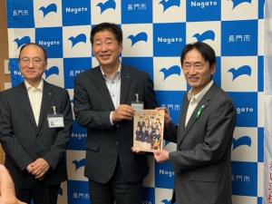 左から伊藤教育長、江原市長と図書を寄贈した有富理事長