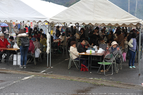 小雨が降ったりやんだりの天候の中、多くの人が来場しグルメを味わう