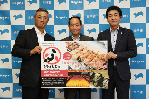 ふるさと名物応援宣言の看板を手に記念撮影