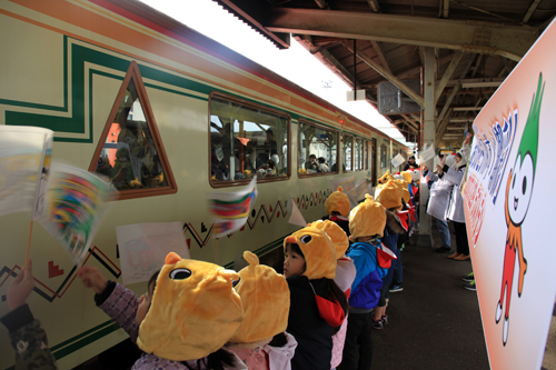 長門市駅に入ってきたみすゞ潮彩に向かって手旗を振って歓迎