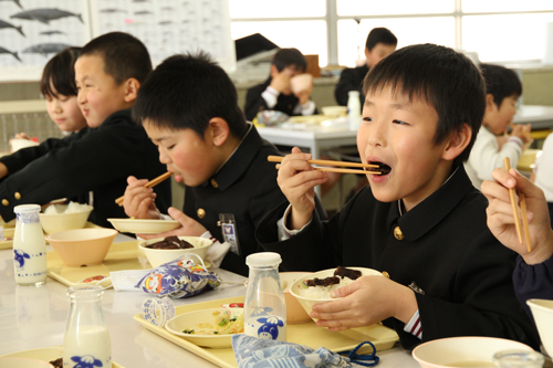 くじらの竜田揚げをほおばる児童
