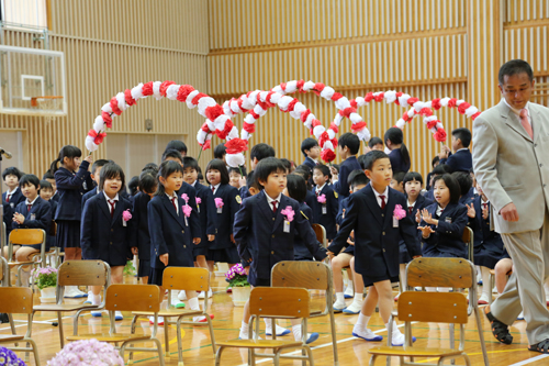 在校生の持つアーチをくぐって入場する新入生