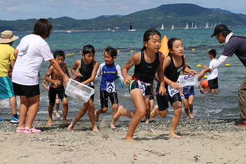 スイムを終え、ゴーグルと帽子を取って砂浜を走る