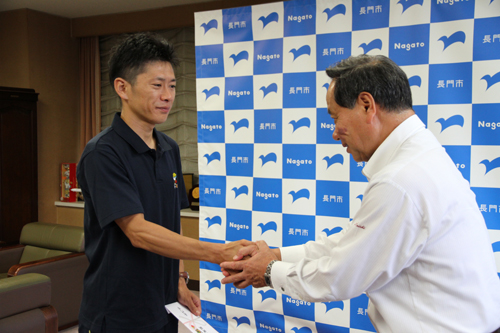 激励費が手渡され、握手を交わす
