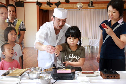 ホテル楊貴館の料理人に指導を受けながら、卵をとじていく作業を体験