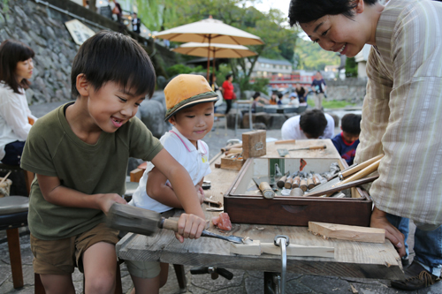 川沿いで木工のワークショップを楽しむ子どもたち