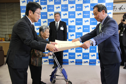 子の鉄哉さんに勲記が、妻の淑枝さんに勲章が手渡される
