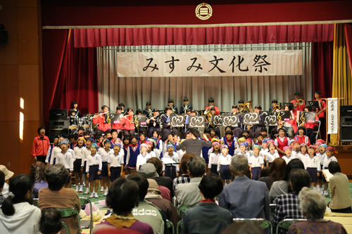 三隅中学校吹奏楽部と「楽々団」の演奏に合わせて、浅田・明倫小学校の児童が歌を披露