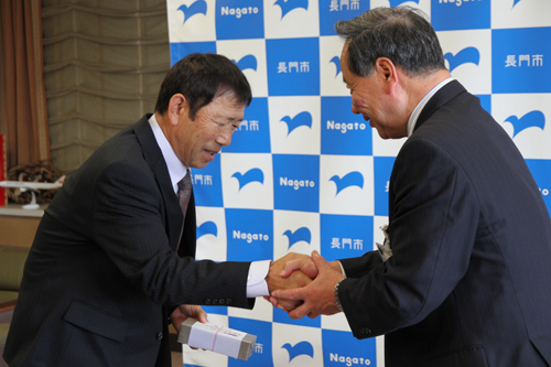 大西市長から記念品を受け取り、握手を交わす