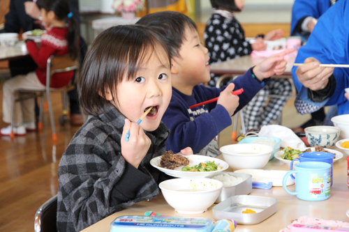 鯨の竜田揚げをほおばる園児