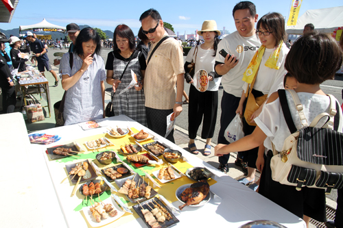 19店舗のやきとりの見本を前に、どれを食べるか悩む来場者