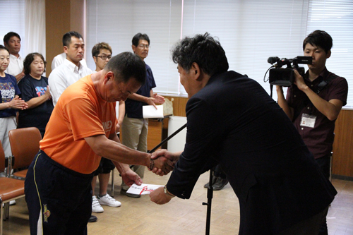 激励費が梶山会長より手渡され、がっちりと握手を交わす