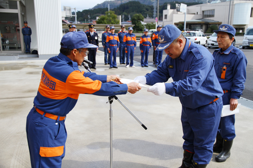 村部消防団長より小型動力ポンプ積載車の目録が手渡される