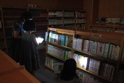 懐中電灯の明かりを頼りに絵本を探す