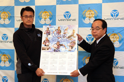 山村常任理事からカレンダーを受け取る白木事務局長