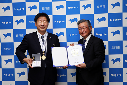 認定証明書とメダルを小川理事長から受け取った江原市長