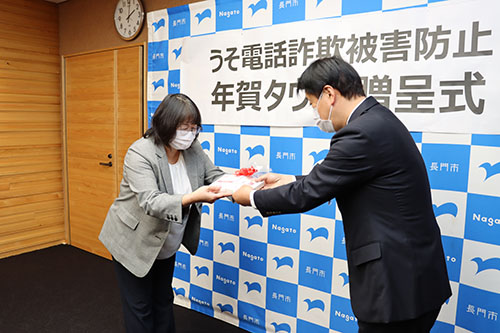 協賛団体を代表して市内で飲食業を営む青村雅子さんから江原市長にはがきが贈呈