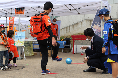 スタジアム外に設置した長門市PRブース。ミニサッカーゲームを楽しむサポーターたち。