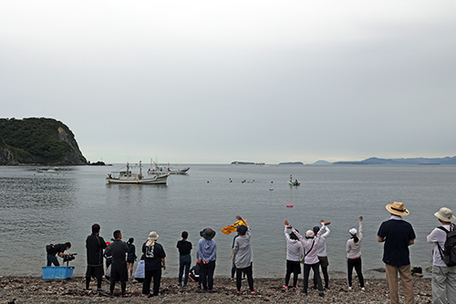 浜から地域の人や保護者が声援を送る