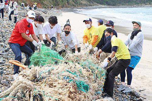 漂流した大きな漁獲用網をみんなで協力して運ぶ