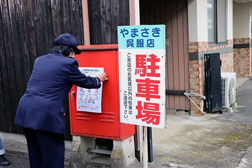 消火栓ボックスに取り扱い方法を張り付ける中山会長