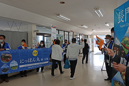 市や県の関係者が横断幕などで乗客を歓迎した