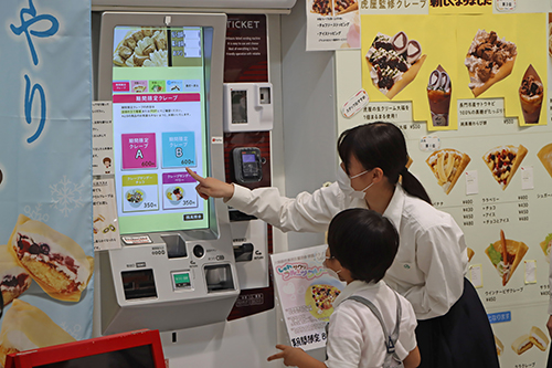 来店したお客さんにご案内をする高校生