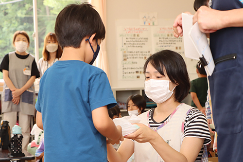 袋に入れて、昼食のお弁当が児童に手渡される