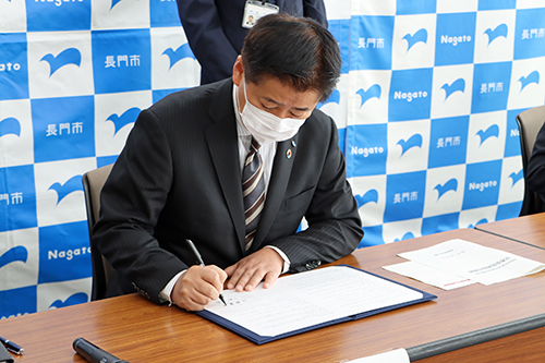 協定書にサインする江原市長