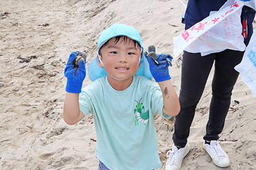 海岸に流れ着いたプラスチックごみを拾う園児