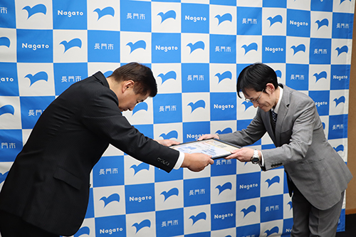 株式会社ダイナムの中村さんから江原市長に目録が手渡された