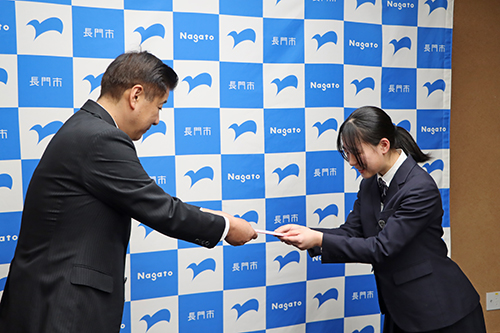 江原市長から激励費とTシャツが手渡された