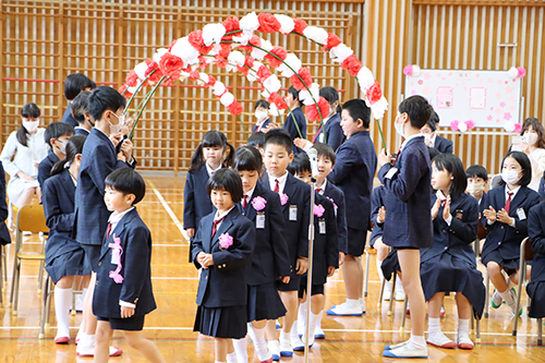 在校生によるアーチをくぐって新1年生が入場する様子
