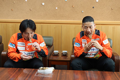 長門の特産品であるやきとりを食べる野寄和哉選手とキムボムヨン選手
