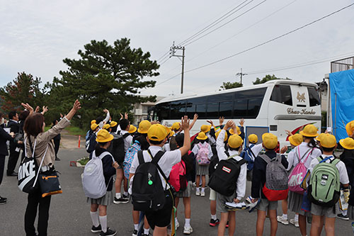名陵小学校児童を乗せたバスを見送る児童たち
